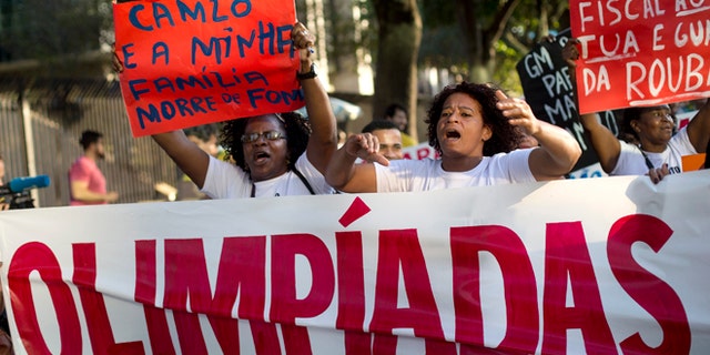 FILE - In this Aug. 5, 2015, file photo, people protest against the 2016 Olympic Games while they hold posters that read in Portuguese "I am a street vendor and my family starves" and "Attorney acts and the police steals," in front of the headquarters of the Olympic Organizing Committee in Rio de Janeiro, Brazil. Brazilâs economic and political crisis has relegated Rio de Janeiro's Olympic preparations to an afterthought. Rio's Olympics are being sidelined by an even bigger show: Brazilian President Dilma Rousseff's fight against impeachment amid multiple corruption scandals with the country mired in the worst economic recession since the 1930s. (AP Photo/Silvia Izquierdo, File)