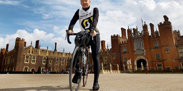 April 20, 2012: In this photo, Surrey County Councils Alan Flaherty, who has been involved in designing the Olympic road cycle course, and helping athletes to test it out, poses for a photograph in front of Hampton Court Palace, Hampton, England.