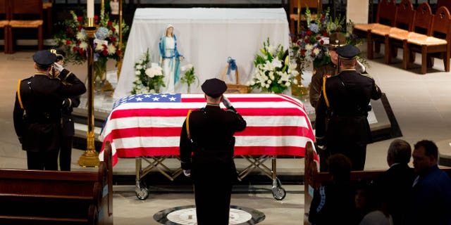 Omaha police officers salute before removing the flag from the top of the casket before the funeral service for Omaha police detective Kerrie Orozco, Tuesday, May 26, 2015 at St. John's Catholic Church at Creighton University in Omaha, Neb. Orozco, 29, was shot and killed May 20, 2015 in Omaha. (Matt Miller/The World-Herald via AP, Pool)