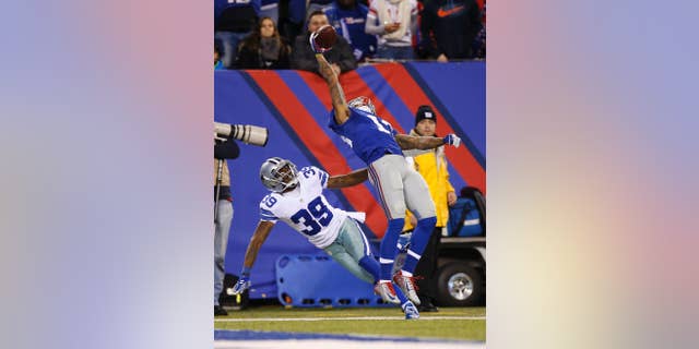 FILE - In this Nov. 23, 2014, file photo, New York Giants wide receiver Odell Beckham Jr. (13) makes a one-handed catch for a touchdown against Dallas Cowboys cornerback Brandon Carr (39) in the second quarter of an NFL football game in East Rutherford, N.J. The one-handed catch by Odell Beckham Jr. that became the most talked-about play from Sunday, Nov. 23, 2014, did more than just boost his standing with the Giants, it paid off a routine growing popular among many skill players of practicing the impractical, one-handed circus grab. (AP Photo/Kathy Willens, File)