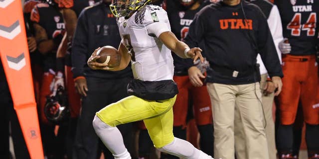 Utah defensive back Marcus Williams (20) tackles Oregon quarterback Marcus Mariota (8) as stretches to make a first down in the first quarter during an NCAA college football game Saturday, Nov. 8, 2014, in Salt Lake City. (AP Photo/Rick Bowmer)