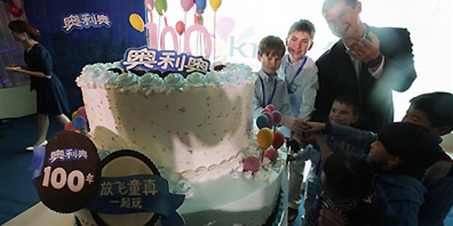 Tuesday March 6, 2012: Shawn Warren, president of Kraft Foods China, back row right, and children cut the birthday cake for Oreo cookie's 100th anniversary celebration in Shanghai, China.