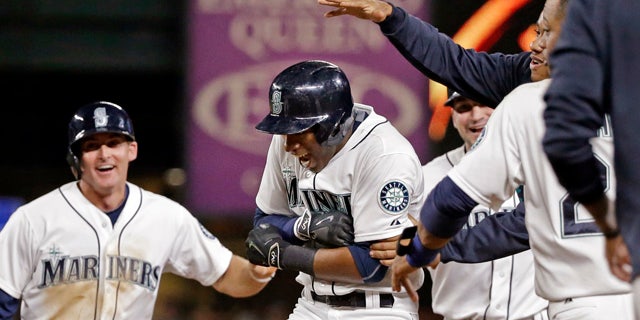 Aug. 11, 2015: Seattle Mariners' Austin Jackson, center, is mobbed by teammates after hitting in the game-winning run against the Baltimore Orioles in the 10th inning of a baseball game in Seattle. The Mariners won 6-5. (AP Photo/Elaine Thompson)
