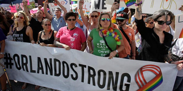 FILE- In this June 18, 2016 file photo, demonstrators show their support during the funeral service for Christopher Andrew Leinonen, one of the victims of the Pulse nightclub mass shooting, outside the Cathedral Church of St. Luke, in Orlando, Fla. Following the attack, other victims of mass shootings reached out to the survivors and their families to ensure that mistakes made with previous charity efforts were not repeated. (AP Photo/John Raoux, File)