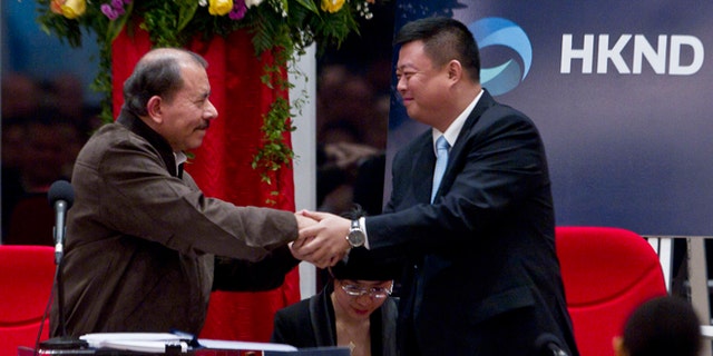 Nicaragua's President Daniel Ortega, left, and Chinese businessman Wang Jing shake hands before signing a concession agreement for the construction of a multibillion-dollar canal at the Casa de los Pueblos in Managua, Nicaragua, Friday, June 14, 2013. Legislation approved by a 61-25 vote in the National Assembly dominated by Ortega's Sandinista Front contains no specific route for the canal and virtually no details of its financing or economic viability, but it grants a Hong Kong-based company 50 years of exclusive rights to study the plan and build and operate a canal in exchange for Nicaragua receiving a minority share of any profits. (AP Photo/Esteban Felix)