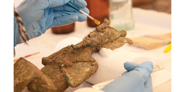 Researchers carefully conserve an Osiris statuette found within the favissa. It's possible the statue of the god Ptah was placed with the Osiris statuettes because Osiris was the god of rebirth.