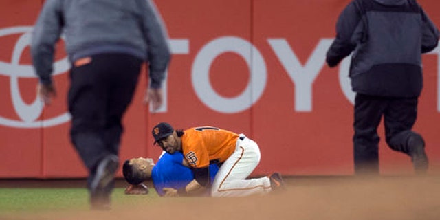 San Francisco Giants Angel Pagan (16) holds down a man who ran onto the field during the fourth inning of the Giants' baseball game against the Los Angeles Dodgers, Friday, Sept. 30, 2016, in San Francisco. (AP Photo/D. Ross Cameron)