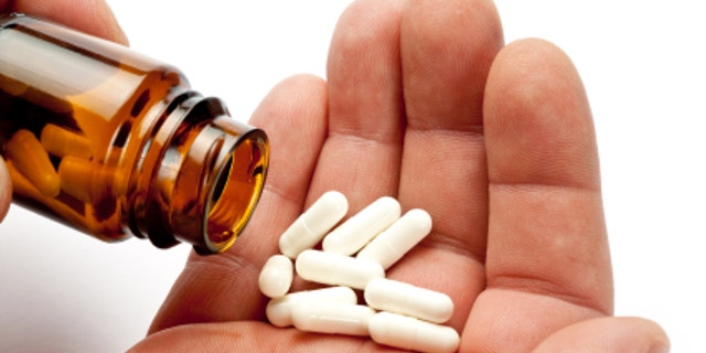 taking drugs. Open glass container and some pills in male hand.