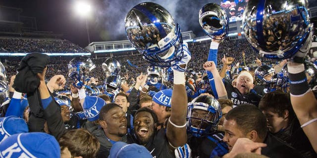 Fans and Kentucky players celebrate together on the field after Kentucky defeated South Carolina 45-38 in an NCAA college football game in Lexington, Ky., Saturday, Oct. 4, 2014. (AP Photo/David Stephenson)