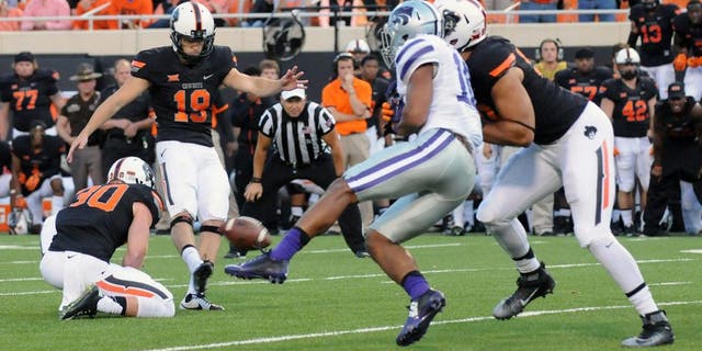 Oklahoma State defensive end Trace Clark, right, defends against Kansas State defensive back Donnie Starks, center right, while Oklahoma State kicker Ben Grogan, center left, kicks the winning field goal held by Oklahoma State holder Bryant Reber, left, during the final seconds of an NCAA football game in Stillwater, Okla., Saturday, Oct. 3, 2015. (AP Photo/Brody Schmidt)