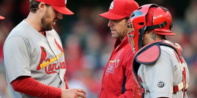 St. Louis Cardinals starting pitcher John Lackey, left, hands the ball off to manager Mike Matheny, center, as catcher Yadier Molina watches in the sixth inning of a baseball game against the Cleveland Indians, Wednesday, May 13, 2015, in Cleveland. Lackey pitched 5 1/3 innings and gave up five hits and two runs. (AP Photo/Tony Dejak)