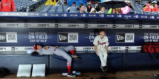 Bat boys wait out a weather-delayed start to the Atlanta Braves against the St. Louis Cardinals baseball game, Saturday, Oct. 3, 2015, in Atlanta. (AP Photo/John Amis)