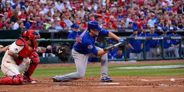 Oct 10, 2015; St. Louis, MO, USA; Chicago Cubs starting pitcher Kyle Hendricks (right) hits a sacrifice bunt against St. Louis Cardinals catcher Yadier Molina (left) scoring Cubs left fielder Austin Jackson (not pictured) during the second inning in game two of the NLDS at Busch Stadium. Mandatory Credit: Jeff Curry-USA TODAY Sports