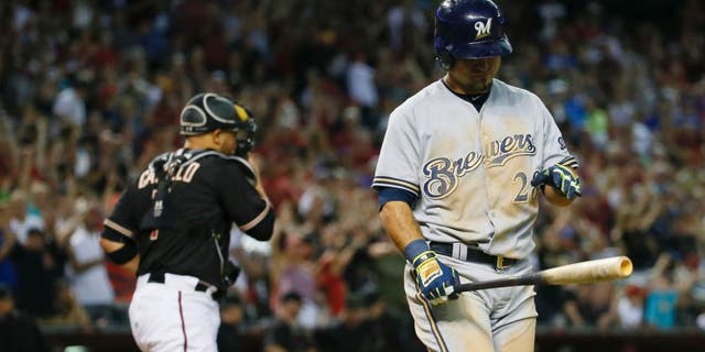 The Milwaukee Brewers' Gerardo Parra walks to the dugout after striking out with the bases loaded to end the game as Arizona Diamondbacks catcher Welington Castillo runs to the mound, Saturday, July 25, 2015, in Phoenix. The Diamondbacks won 2-0.