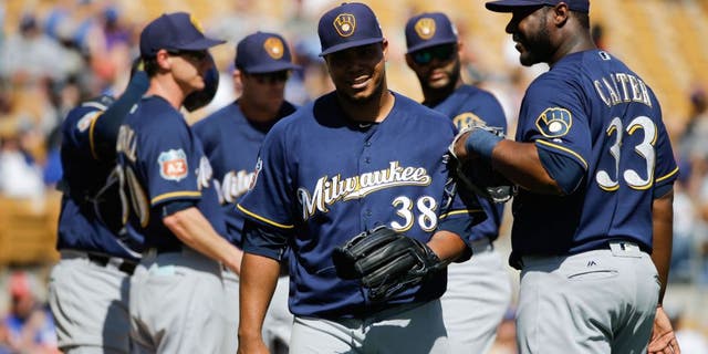 Milwaukee Brewers starting pitcher Wily Peralta, center, walks off the mound past Chris Carter, right, after he was relieved during the fourth inning of a spring training baseball game against the Los Angeles Dodgers Monday, March 14, 2016, in Phoenix.