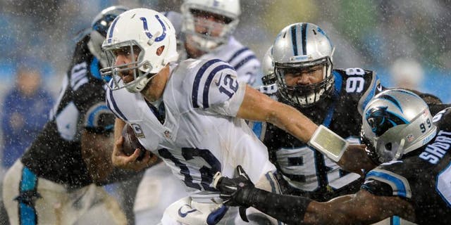Indianapolis Colts' Andrew Luck (12) runs as Carolina Panthers' Kawann Short (99) defends in the first half of an NFL football game in Charlotte, N.C., Monday, Nov. 2, 2015. (AP Photo/Mike McCarn)