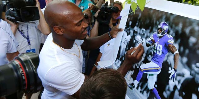 Minnesota Vikings running back Adrian Peterson signs autograph as he reports to an NFL football training camp at Minnesota State University Saturday, July 25, 2015, in Mankato, Minn.