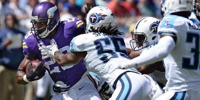 Minnesota Vikings running back Adrian Peterson tries to get past Tennessee Titans defenders including Sean Spence in the first half Sunday, Sept. 11, 2016, in Nashville, Tenn.