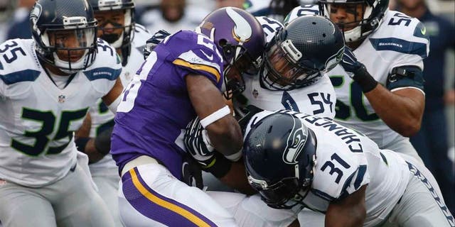 Minnesota Vikings running back Adrian Peterson is stopped by Seattle Seahawks defenders including linebacker Bobby Wagner (center) and strong safety Kam Chancellor (bottom right) in the first half of an NFL football game Sunday, Dec. 6, 2015 in Minneapolis.