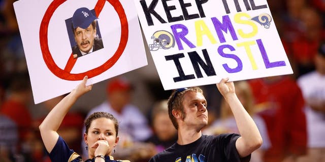Fans hold up signs with a picture of St. Louis Rams owner Stan Kroenke and "Keep the Rams in STL" during a baseball game between the St. Louis Cardinals and Los Angeles Dodgers, Friday, May 29, 2015, in St. Louis. (AP Photo/Billy Hurst)