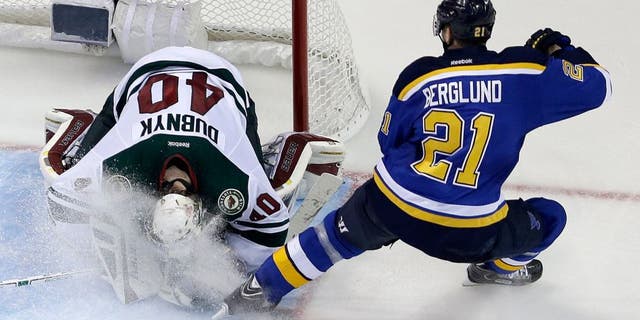 Minnesota Wild goalie Devan Dubnyk, left, smothers a puck as he is sprayed by St. Louis Blues' Patrik Berglund, of Sweden, during the third period in Game 2 of an NHL hockey first-round playoff series, Saturday, April 18, 2015, in St. Louis. The Blues won 4-1 to tie the series 1-1. (AP Photo/Jeff Roberson)