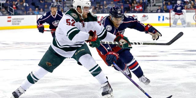 Minnesota Wild defenseman Zach Palmquist skates against Columbus Blue Jackets left wing Rene Bourque.