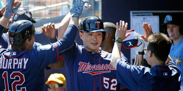 FILE - In this March 6, 2016, file photo, Minnesota Twins' Byung Ho Park, center, of South Korea, high-fives teammates in the dugout after hitting a grand slam in the first inning of a spring training baseball game against the Tampa Bay Rays in Port Charlotte, Fla. The Korean slugger is excited about making the transition from his native homeland to the major leagues this season and aims to make noise with his bat while quietly going about his business off the field and getting acclimated to life more than 7,500 miles from Seoul. (AP Photo/Patrick Semansky, FILE)