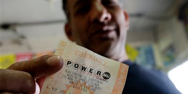 Joe Fajardo poses holding his Powerball lottery ticket after buying it at a store Saturday, May 18, 2013, in the Barrio Logan neighborhood of San Diego. With the majority of possible combinations of Powerball numbers in play, someone is almost sure to win the lottery game's highest jackpot on Saturday night, a windfall of hundreds of millions of dollars and that's after taxes. (AP Photo/Gregory Bull)