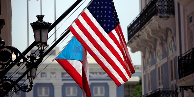 FILE - In this June 29, 2015 file photo, U.S. and Puerto Rico flags hang outside the governors mansion in Old San Juan, Puerto Rico. Puerto Rico is entering its ninth year of recession and is struggling with billions in public debt that Gov. Alejandro Garcia Padilla has said is unpayable given the current economic conditions. (AP Photo/Ricardo Arduengo, File)