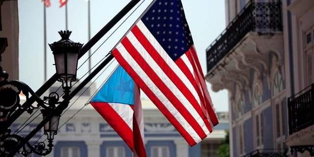 FILE - In this June 29, 2015 file photo, U.S. and Puerto Rico flags hang outside the governors mansion in Old San Juan, Puerto Rico. Puerto Rico is entering its ninth year of recession and is struggling with billions in public debt that Gov. Alejandro Garcia Padilla has said is unpayable given the current economic conditions. (AP Photo/Ricardo Arduengo, File)