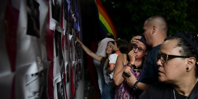 Residents look at photos of the victims during a vigil to honor the memory of the Puerto Ricans that died in the mass shooting at a nightclub in Orlando, Fla., at the Hato Rey LGBTT Community Center in San Juan, Puerto Rico, Tuesday, June 14, 2016. Dozens of people died at the 'Pulse' gay nightclub in Orlando, making it the deadliest mass shooting in modern U.S. history. (AP Photo/Carlos Giusti)