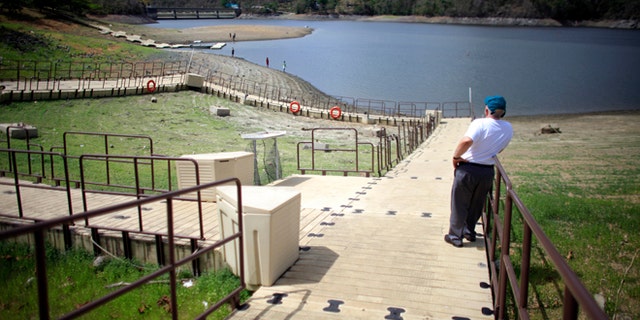 A man stands on a floating dock, laying on the unusually dry banks of the La Plata reservoir in Toa Alta, Puerto Rico, Wednesday, May 13, 2015. Puerto Rico imposed strict water-rationing measures Wednesday and Gov. Alejandro Garcia Padilla recently declared a state of emergency given the increasingly dry conditions. (AP Photo/Ricardo Arduengo)