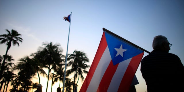 FILE - In this April 30, 2015, file photo, people gather in front of the Puerto Ricoâs Capitol building to protest against Gov. Alejandro Garcia Padilla's budget proposal for the next fiscal year in San Juan. Authorities announced on Monday, Jan. 18, 2016, that Puerto Rico's worsening economic crisis has forced it to revise a fiscal reform plan to reflect a jump in the island's projected deficit and a steep drop in anticipated revenue. (AP Photo/Ricardo Arduengo, File)