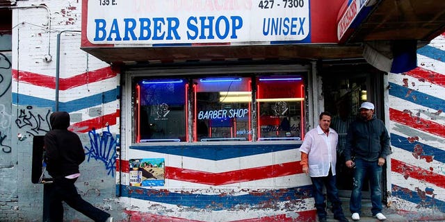 NEW YORK - JANUARY 06: Men stand outside a barber shop as the Three Kings Day Parade passes in East Harlem January 6, 2009 in New York City. The parade celebrates the Feast of the Epiphany, also known as Three Kings Day, marking the Biblical story of the visit of three kings to Bethlehem to visit the baby Jesus, revealing his divinity. (Photo by Mario Tama/Getty Images)