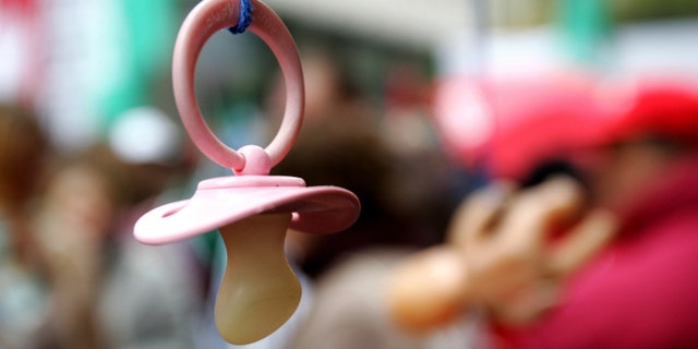 A baby pacifier hangs from an umbrella as part of the props used by union workers in a non-profit sector march in Brussels December 2, 2005. Workers held protests in different parts of the country in the latest public demonstration against a government proposal to postpone early retirement, which they argue will keep young people out of work. REUTERS/Francois Lenoir