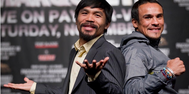 Manny Pacquiao, left, jokes with members of the media while posing for photos with Juan Manuel Marquez during a news conference Wednesday, Nov. 9, 2011, in Las Vegas. Pacquiao and Marquez are scheduled to meet for boxing's WBO welterweight title on Saturday. (AP Photo/Julie Jacobson)