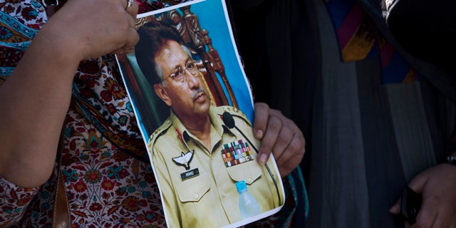 March 31, 2014: A supporter of former Pakistani President Pervez Musharraf holds a photo of him outside the special court in Islamabad. A special court Monday indicted former military ruler Musharraf on five counts of high treason, marking a sharp blow to the country's powerful military. (AP Photo/B.K. Bangash)