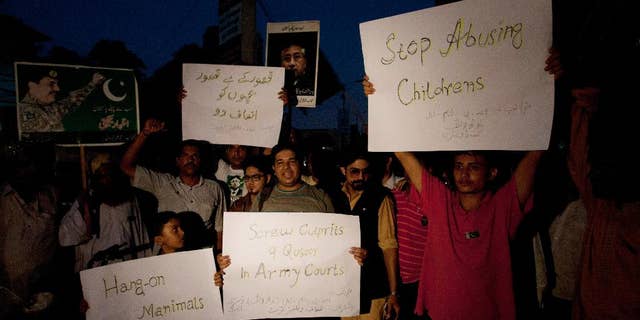 Activists from Pakistan's civil society hold placards to condemn a child abuse scandal, while holding a rally in Karachi, Pakistan, Tuesday, Aug. 11, 2015. In the Pakistani town of Hussain Khan Wala, near the border with India, families kept quiet for years about the blackmail gang that locals believe filmed some 270 children being sexually abused, fearful the videos could appear online or sold in markets for as little as 50 cents. The placard at upper left reads in Urdu, "Give justice to innocent children." (AP Photo/Shakil Adil)