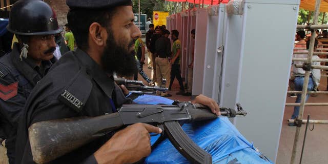 Pakistani police officers stand alert at an entrance of the Gaddafi stadium during the second one-day international match between Pakistan and Zimbabwe Friday, May 29, 2015. Zimbabwe is the first test playing nation to visit Pakistan in more than six years since gunmen attacked a bus of the Sri Lanka team in Lahore in 2009. (AP Photo/K.M. Chaudary)