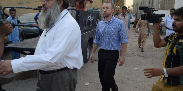 An American national, center, reportedly working for the FBI, leaves a police station in Karachi, Pakistan, Thursday, May 8, 2014. Pakistan released an FBI agent on bail Thursday after three days in custody, officials said, a move that is likely to prevent the situation from escalating into a diplomatic spat. The American man was detained after airport authorities found him carrying ammunition and three knives Monday as he was about to board a flight for the Pakistani capital, Islamabad.(AP Photo/Mohammad Khalil)