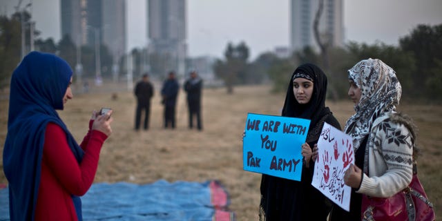 Dec. 19, 2014 - A Pakistani university student takes a picture of her friends holding banners prior to a protest condemning Tuesday's Taliban attack on a military-run school in Peshawar, in Islamabad, Pakistan that left 148 dead. Pakistani warplanes and ground forces killed at least 77 militants in a northwestern tribal region near the Afghan border.