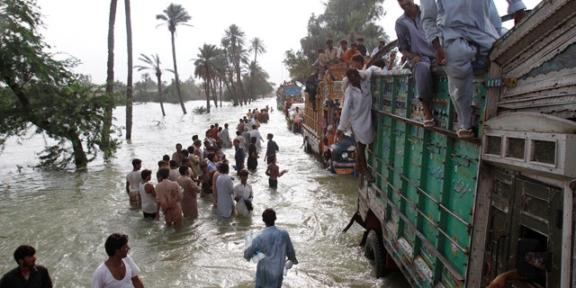 August 18: Flood survivors carry relief goods along a flooded area in Muzaffargarh, Punjab province, in Pakistan. (AP)