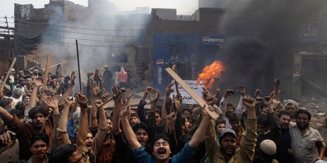 An angry mob reacts after burning Christian houses in Lahore, Pakistan, on Saturday. (AP Photo/K.M. Chaudary)