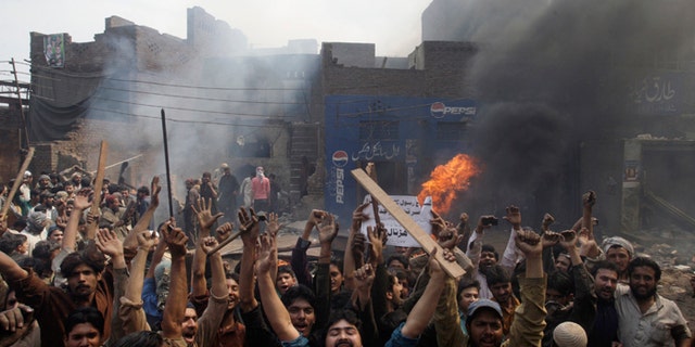 An angry mob reacts after burning Christian houses in Lahore, Pakistan, on Saturday. (AP Photo/K.M. Chaudary)