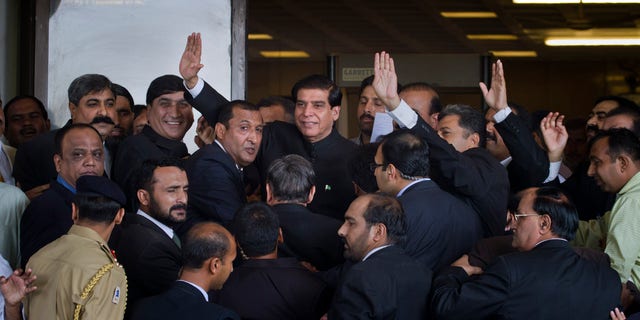 Aug. 27, 2012: Pakistan's Prime Minister Raja Pervaiz Ashraf, center, waves as he is surrounded by security staff upon his arrival at the Supreme Court for a hearing in Islamabad, Pakistan.