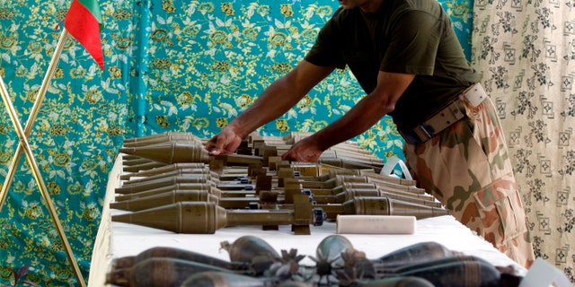 A Pakistani army soldier arranges weapons reportedly recovered from hideouts of militants in tribal areas, as they are displayed in Peshawar, Pakistan on Wednesday, Aug. 29, 2012. (AP Photo/Mohammad Sajjad)