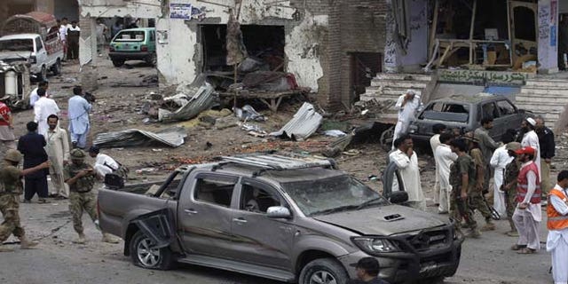 June 30, 2013: Pakistani security officials and rescue workers examine the site of car bombing on the outskirts of Peshawar, Pakistan. A car bomb exploded as a convoy of paramilitary troops passed through the outskirts of the northwest Pakistani city of Peshawar, killing more than a dozen people and wounding scores of others, police said.