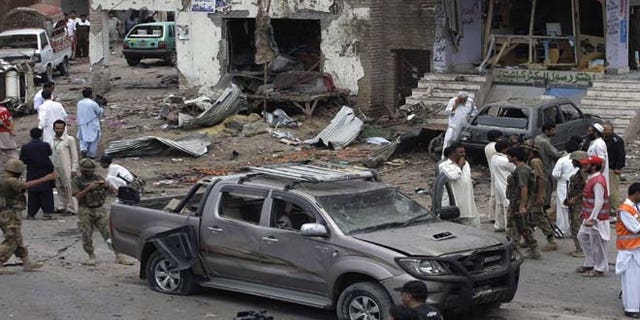 June 30, 2013: Pakistani security officials and rescue workers examine the site of car bombing on the outskirts of Peshawar, Pakistan. A car bomb exploded as a convoy of paramilitary troops passed through the outskirts of the northwest Pakistani city of Peshawar, killing more than a dozen people and wounding scores of others, police said.