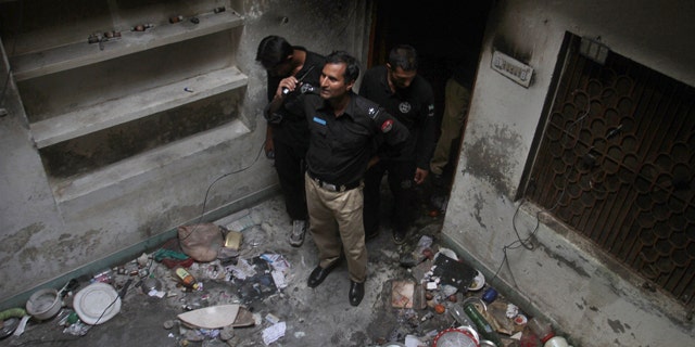 July 28, 2014: Pakistani police officers examine a house of a family belonging to the Ahmadi sect, which was torched by angry mob in Gujranwala, Pakistan. (AP Photo/K.M. Chaudary)