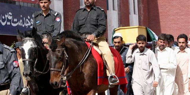 May 18: Pakistani police officers ride horses in front of relatives of one of two officers, who were killed in an attack by militants at a security checkpoint, carrying his body during his funeral procession in Peshawar, Pakistan.